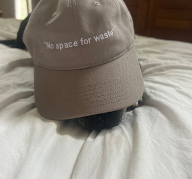 Eco-friendly 'No Space For Waste' embroidered hat, made from 100% cotton canvas, featuring a sleek low profile and curved peak for sustainable fashion enthusiasts.
